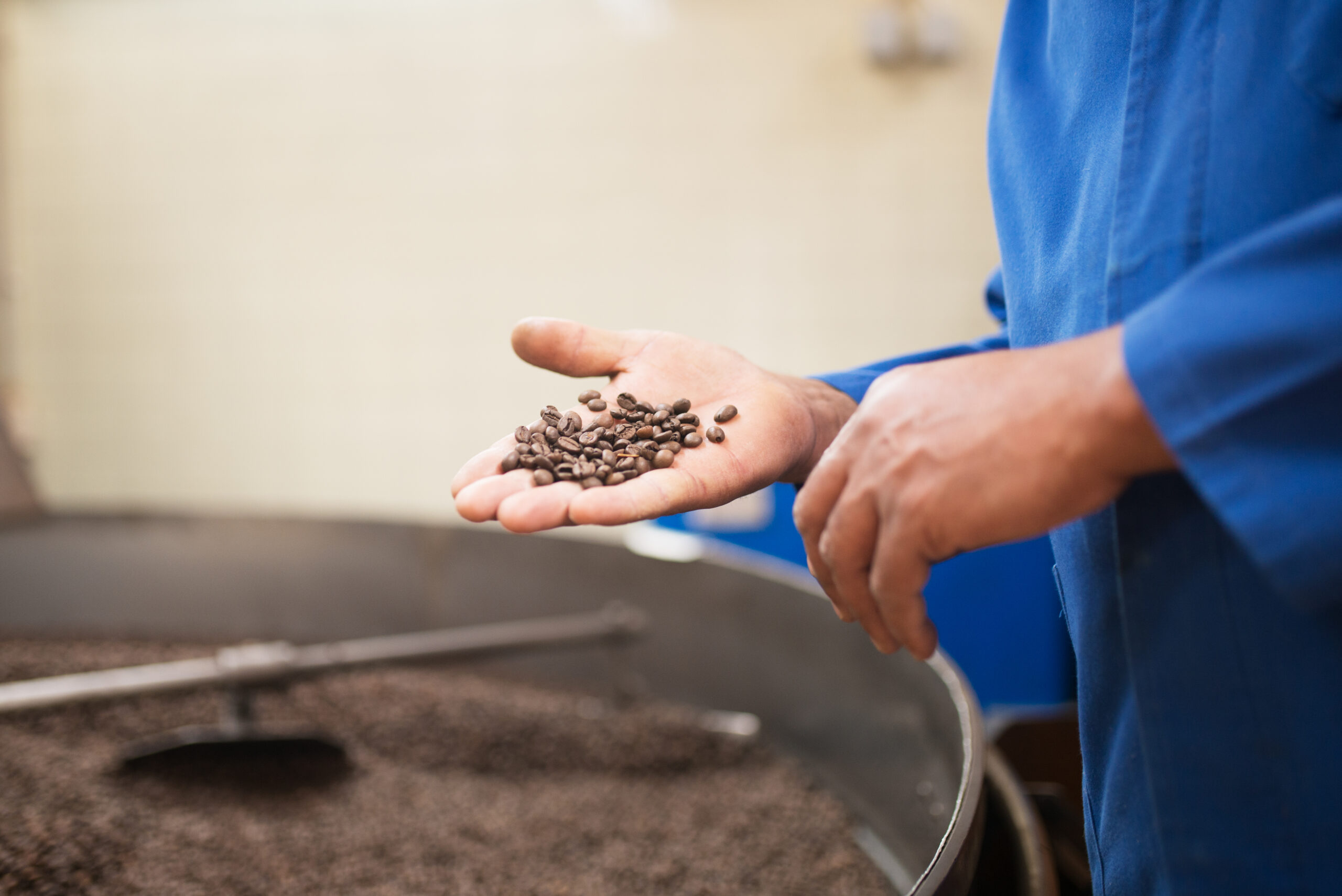 close-up-man-holding-roasted-coffee-beans-scaled.jpg
