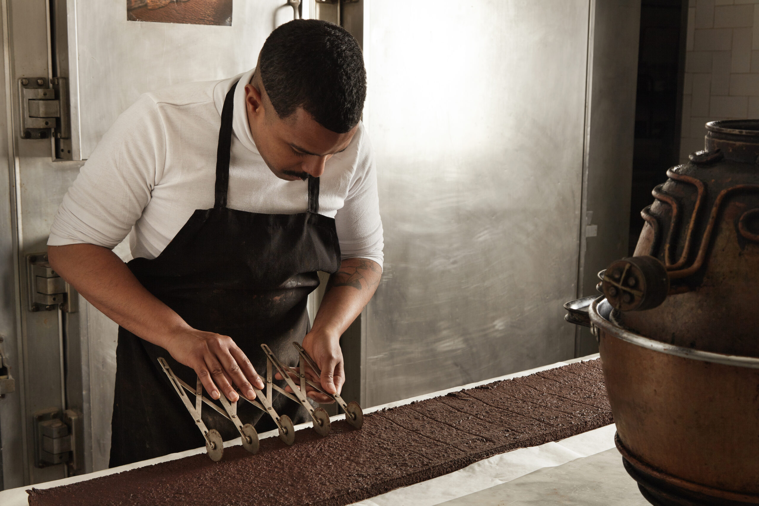 side-view-black-man-chief-use-professional-vintage-separator-split-chocolate-cake-equal-portions-before-packaging-artisan-cooking-process-confectionery-scaled.jpg